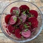 Close-up of canned pickled beets in a bowl with herbs